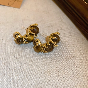 Détail macro de boucles d'oreilles rétro dorées avec trois perles léopard sur lin