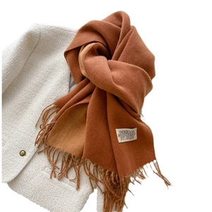 Brown double-sided cashmere-like scarf with fringe tassels on a white jacket