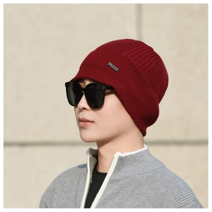Close-up of deep red knitted winter beanie with NY&JA logo tag and ribbed texture