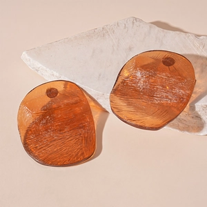 Macro detail of amber resin earrings with ice-crack texture on white stone base