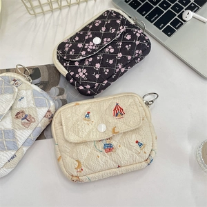 Detailed view of quilted cotton pouches in floral and circus bear patterns with metal ring