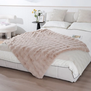 Close-up of thick faux rabbit fur blanket with wavy textured pattern in light camel color