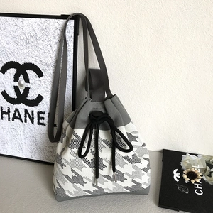 Detail of knitted bucket bag showing houndstooth pattern and black drawstring closure