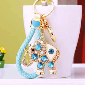 Crystal elephant keychain with blue braided rope and rhinestones on a white cup
