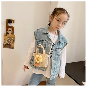 Kid beige straw crossbody bag featuring large yellow and orange plush flower decorations