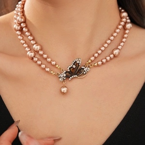 Detail of double-layer champagne pearl necklace featuring a crystal butterfly pendant