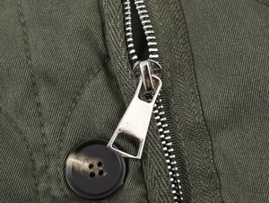 Close-up of metallic zipper and dark resin button on army green twill jacket