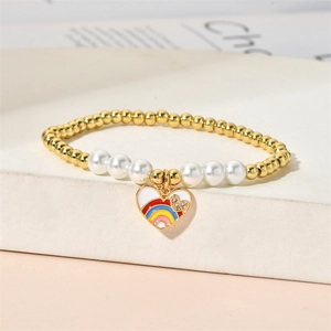 Close-up of beaded bracelet with gold metal balls, pearls, and rainbow heart charm