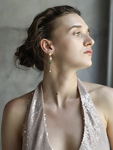 Elegant 18K gold plated long tassel earrings with green gems and pearls on a model