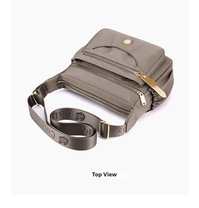 Detail view of taupe multi-zipper waterproof nylon crossbody bag with wide logo strap