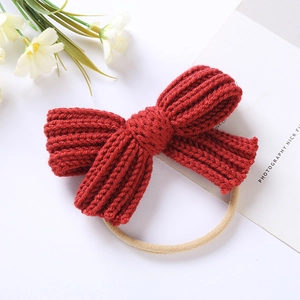 Close-up of red knitted bow baby headband with soft nylon texture on white background