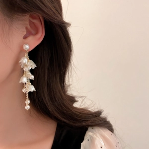 Eleganti orecchini a nappa con mughetto e perle finte indossati da una modella