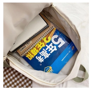 Interior view of off-white canvas backpack showing spacious capacity for books and notebooks
