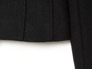 Close-up of black wool fabric texture with parallel decorative stitching on the hemline
