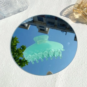 Detail of mint green frosted acetate hair claw clip reflecting in a circular mirror