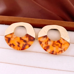 Detailed macro view of amber acrylic round hoop earrings with golden hammered metal finish