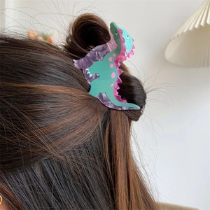 Detail view of cute green acrylic dinosaur hair claw clip styled on a woman bun