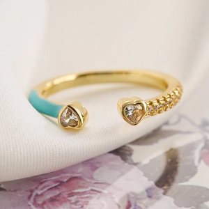 Dettaglio dell'anello a cuore dorato con smalto celeste e accenti in zircone