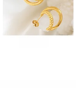 Macro detail of golden C-shaped hoop earrings with layered twisted and smooth texture