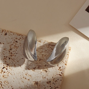 Macro shot of silver crescent earrings with vertical brushed texture on stone