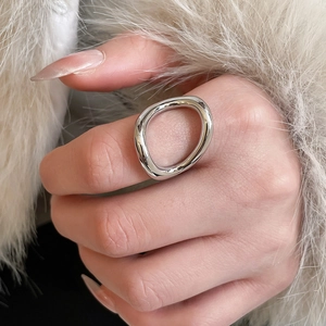 Macro shot of a polished silver irregular organic ring worn on a finger over white fur