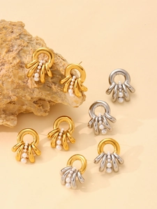 Detail view of octopus style stainless steel earrings with white pearls in gold and silver