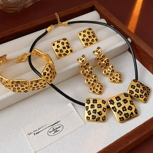 Detail of vintage matte gold jewelry set featuring leopard enamel and amber stones