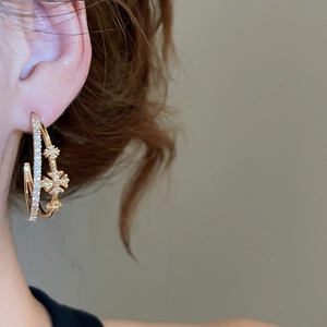 Gros plan de boucles d'oreilles fleurs en C à double couche plaquées or 18 carats