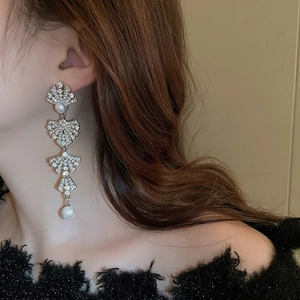 Elegant silver tassel earrings with pearls and crystals worn by a model in profile