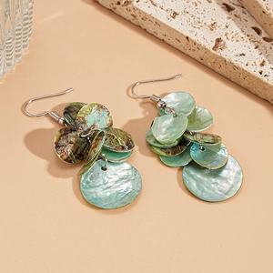 Detail of green shell geometric round earrings on stone showing natural texture and gloss