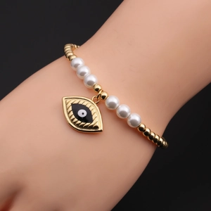 Gros plan d'un pendentif œil maléfique en cœur et de perles dorées sur bracelet