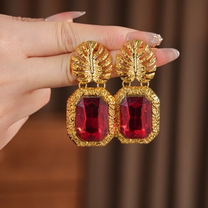 Détail macro de boucles d'oreilles vintage en forme de feuille d'or avec pierre rouge