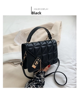 Détail du sac matelassé noir avec chaîne et boucle dorée sur un blazer beige chic