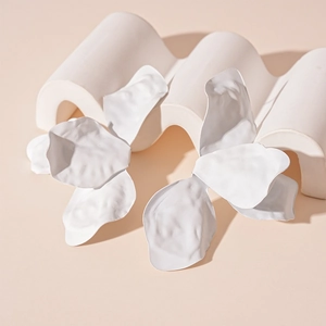 Detailed view of white matte petal earrings with artistic folds on minimalist stand