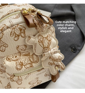 Détail du sac à dos crème avec imprimé ours et breloque en cuir assortie