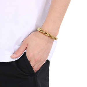 Détail d'un bracelet byzantin épais en finition dorée porté au poignet d'un mannequin homme