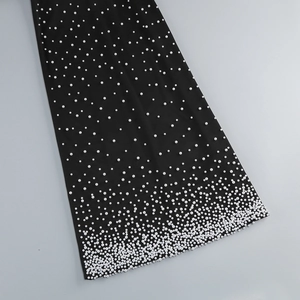 Detailed view of white pearls gradient pattern on black fabric of the evening gown