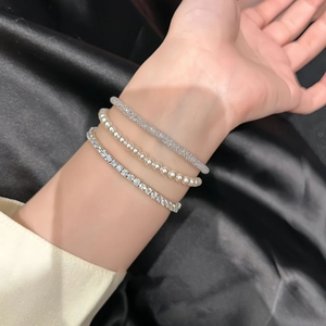 Three-piece silver bracelet set with pearls and zircon bangles on black silk background
