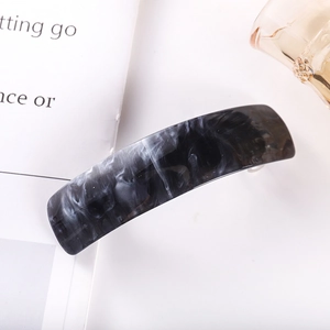 Detail of marble pattern acetate hair clip with metal spring on decorative background