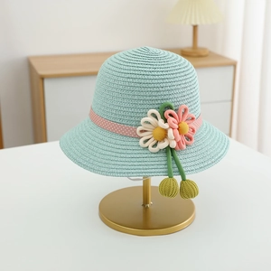Detail of mint green straw hat with pink dotted ribbon and handmade crochet flowers