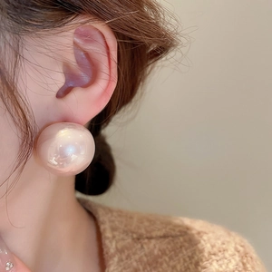 Primo piano di un grande orecchino a perla tonda rosa champagne indossato da una modella