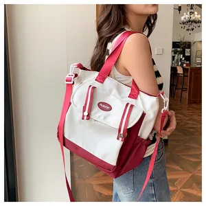 Detail of color-block canvas crossbody tote featuring red strap and fashion label pocket