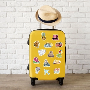 Detailed view of VSCO aesthetic waterproof stickers on a yellow suitcase with travel motifs