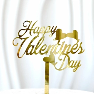 Close-up of gold acrylic Happy Valentine's Day cake topper with two hearts and glossy finish