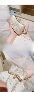 Detail of champagne evening clutch with silk pleats, pearl handle and pearl clasp closure