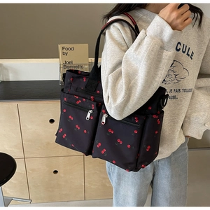 Close-up of black canvas tote bag with cherry print and functional double front pockets