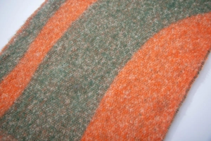 Close-up of orange and green textured jacquard scarf with soft plush boucle yarn details