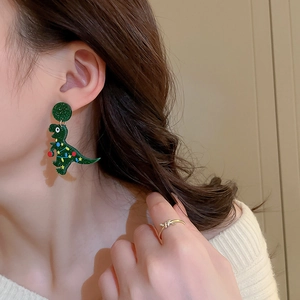 Cute green acrylic Christmas dinosaur earrings paired with a gold zircon knot ring