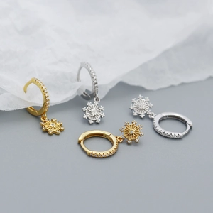 Macro shot of silver and gold eight-pointed star hoop earrings with sparkling cubic zirconia