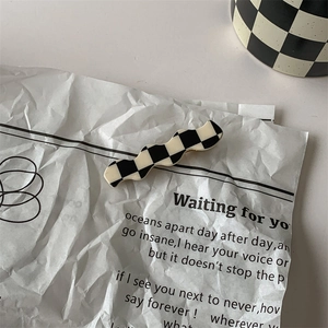 Detail of a black and white checkerboard wavy hair clip made of smooth acrylic material
